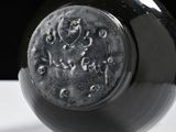 a close up of a black vase on a white table