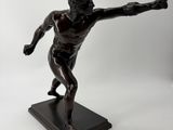 bronze statue of a man throwing a frisbee on a black base