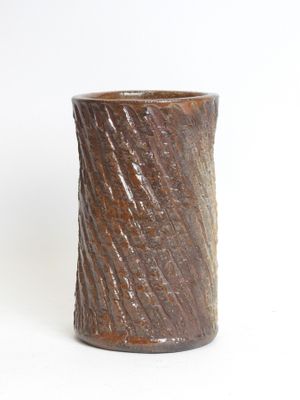 a brown vase that is sitting on a white surface