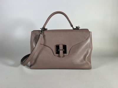 a brown handbag sitting on top of a table next to a white wall