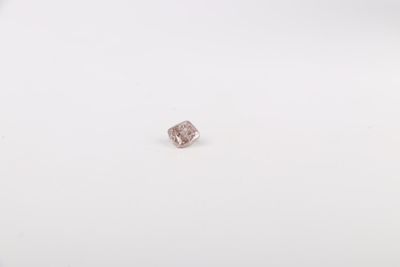 une image représentant un diamant rose posé sur une surface blanche
