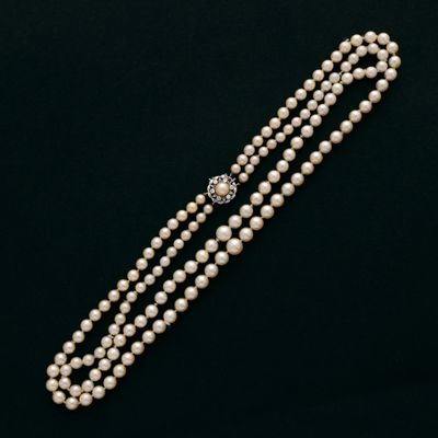 un collier de perles avec un fermoir en diamant sur fond noir