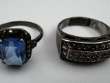 two rings with a blue stone in them sitting on a white surface