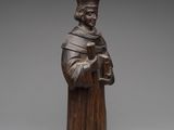 a wooden statue of a man holding a book and wearing a hat