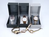 trois montres et un bracelet dans un coffret posé sur une surface blanche