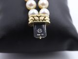 a close up of a black purse with a pearl necklace on it