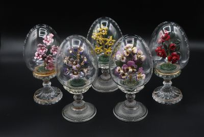 six vases en verre contenant des fleurs, posés sur une surface noire