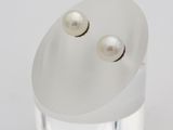 a close up of a pair of pearl earrings on a clear surface
