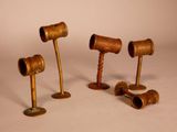three antique wooden mallets are lined up on a white surface