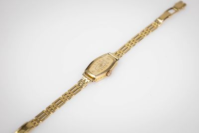gros plan d'une montre en or sur une surface blanche