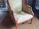 an old chair in a living room with a plant in the corner