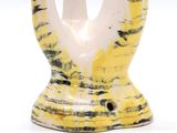 a yellow and white vase with a black and white design on it