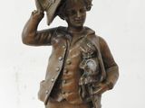 bronze statue of a boy with a hat and a bird on his head
