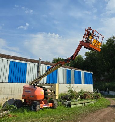 un homme sur une nacelle élévatrice, en train de travailler sur la façade d'un immeuble
