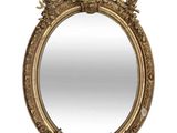 un miroir ovale doré dont le pourtour est orné d'un motif élaboré