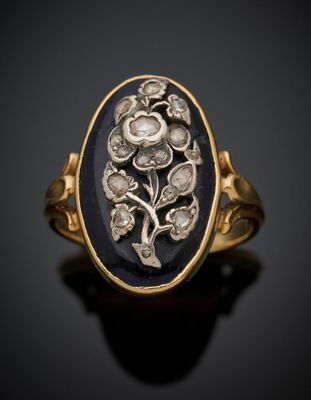 une bague en or sertie d'une pierre noire ovale, entourée de fleurs et de feuilles