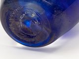 a blue glass bottle that has a small amount of writing on it