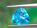 une topaze bleue tenue par une paire de pinces