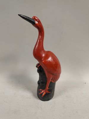a red bird that is sitting on top of a black vase