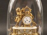 une horloge en or sous un dôme de verre sur une table