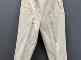 a white pants hanging on a hanger against a gray wall