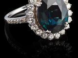 une bague ovale sertie d'un saphir bleu et de diamants, posée sur un fond noir