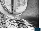 a black and white photo of a bed with a round window