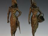 pair of bronze statues of a woman and a man holding a watering can