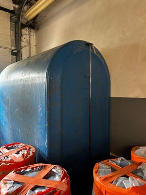 a large blue tank sitting next to a bunch of orange barrels
