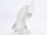 a glass figurine of a bird on a white surface