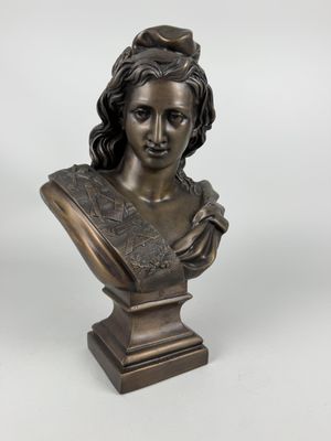 a bronze bust of a woman with a hat on her head