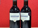 two bottles of wine sitting on top of a wooden table next to a red wall