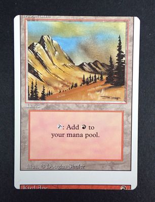 a close up of a card on a table with a mountain in the background