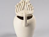 a small white vase with a handle on a gray background
