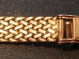 an image of a close up of a gold bracelet on a black surface