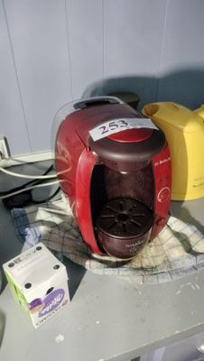 a red coffee maker sitting on a counter next to a box of milk