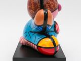 statue of a man sitting on top of a skateboard on a black platform