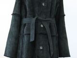 un manteau noir à col de fourrure posé sur un présentoir pour mannequin