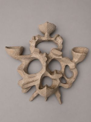 sculpture of a skull made out of clay on a gray surface