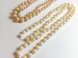 trois rangées de perles sont disposées en ligne sur une surface blanche