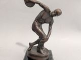bronze statue of a man throwing a basketball ball on a marble base