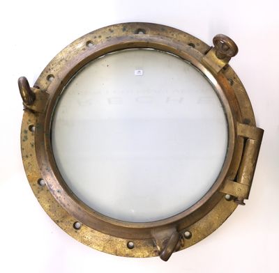 miroir en forme de hublot en laiton sur un mur blanc, avec un fond blanc