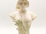 a white ceramic bust of a woman holding a bunch of flowers