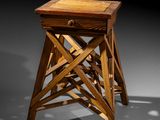 a wooden stool with a drawer on top of it in a dark room