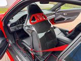 the interior of a red sports car with the door open