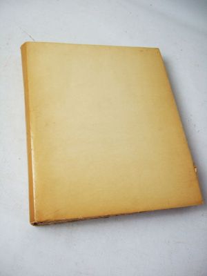 an old book sitting on top of a white table covered in paper
