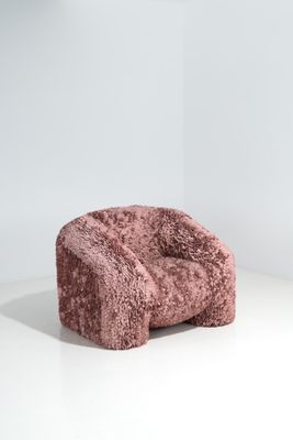 une chaise rose posée sur une surface blanche