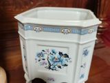 a white planter with blue flowers on it sitting on a table