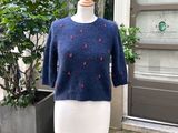 un pull bleu orné de cerises rouges, présenté sur un mannequin