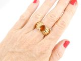 a woman ' s hand holding a gold ring with a stone on it